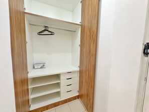Un armario vestidor con paneles de madera, una barra para colgar ropa y varios cajones.