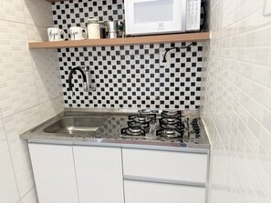 Uma cozinha com fogão a gás, micro-ondas e pia.