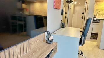 A modern office space with a wooden desk, a chair, a small statue, and a kitchen area in the background.