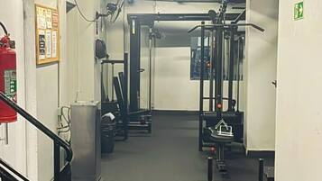 A gym with exercise equipment, a fire extinguisher, and a stairway.