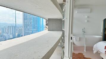A high-rise hotel room with a city view, a bathtub, and a balcony.