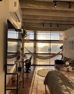 A modern living room with a hammock, large windows, and a view of the city.