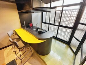 A modern kitchen with a curved island, bar stools, and a large window with a view of buildings. - 0141F (São Paulo)