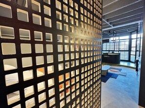 A room with a modern design, featuring a patterned wall with square cutouts and a visible seating area with a table and chairs. - 0141F (São Paulo)