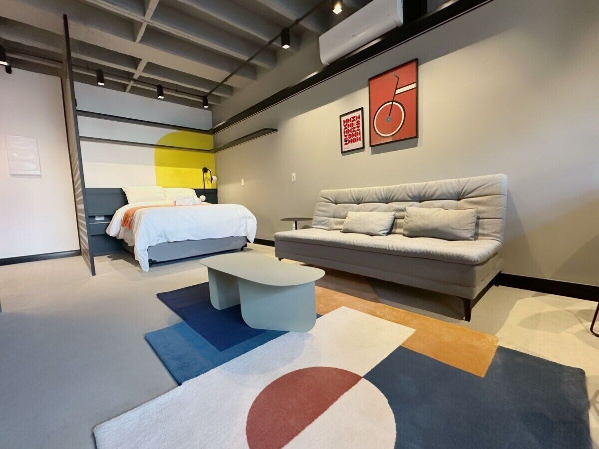 Une chambre d’hôtel moderne avec un lit, un canapé, une table basse et un tapis.