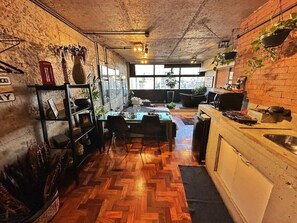 A dining area with a herringbone floor, a table set for two, and a brick wall with hanging plants. - 3013M (São Paulo)