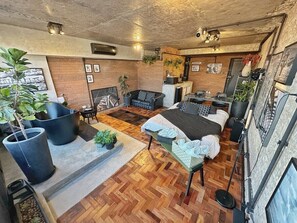 A modern interior with a herringbone wood floor, a sofa set, a bed with a patterned cover, and a fireplace. - 3013M (São Paulo)