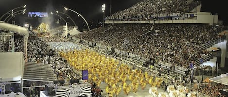 Un stade rempli de spectateurs et d’artistes vêtus de costumes jaunes et blancs.
