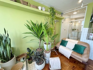 A living room with a sofa, a coffee table, and various potted plants. - 2815M (São Paulo)