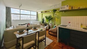 A modern living space with a dining area, a kitchen, and a large window offering a city view. - 2815M (São Paulo)