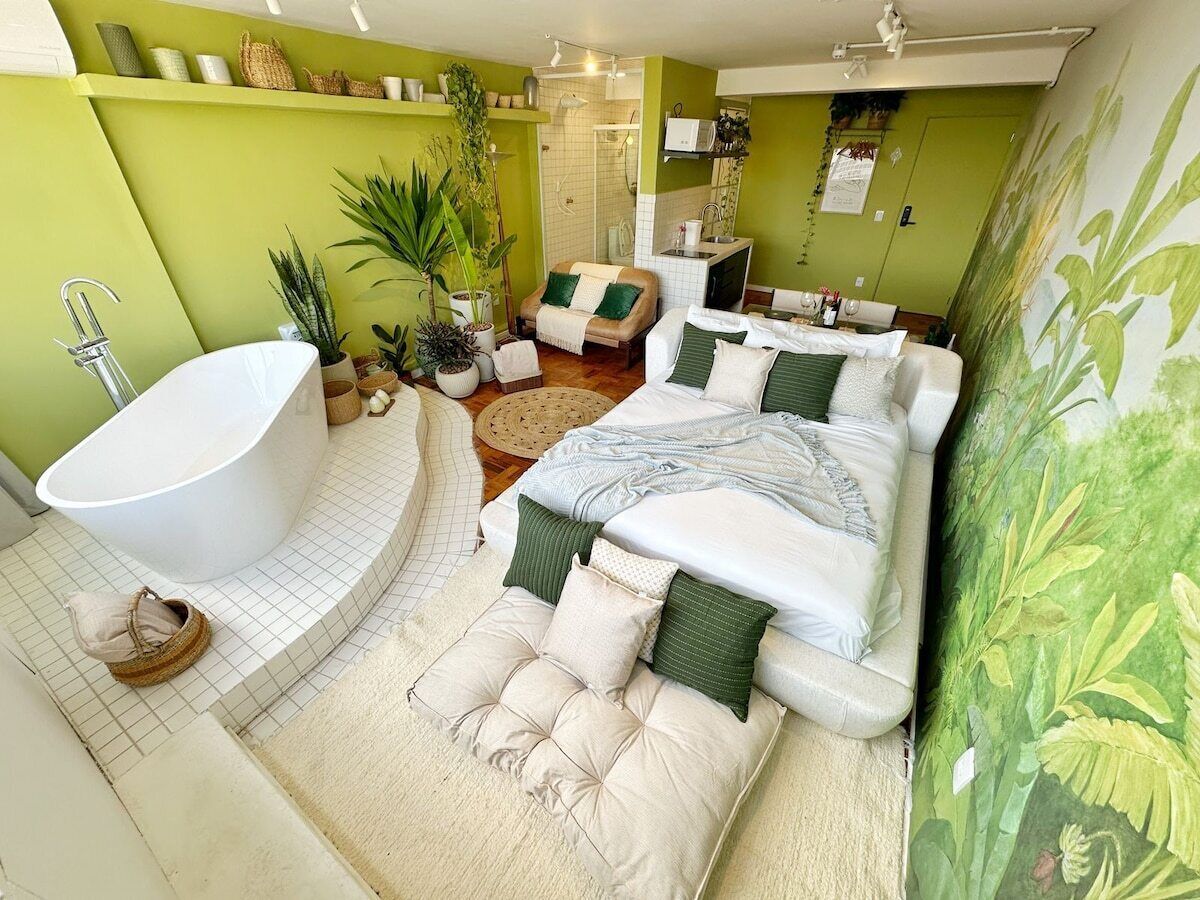 A modern bathroom with a freestanding bathtub, a shower area, and a seating space with a sofa and armchairs.