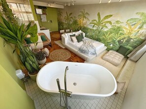 Ein Badezimmer mit einer Badewanne, einer Couch und einem Wandbild einer Dschungellandschaft.