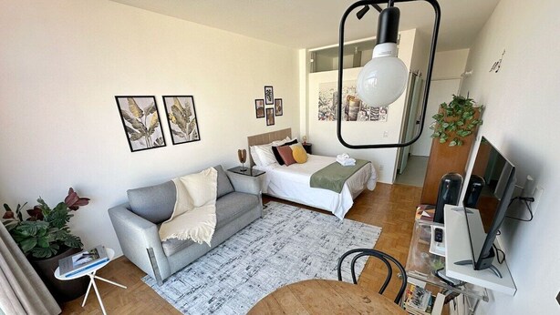Een moderne woonkamer met een grijze bank, een houten eettafel en een televisie.