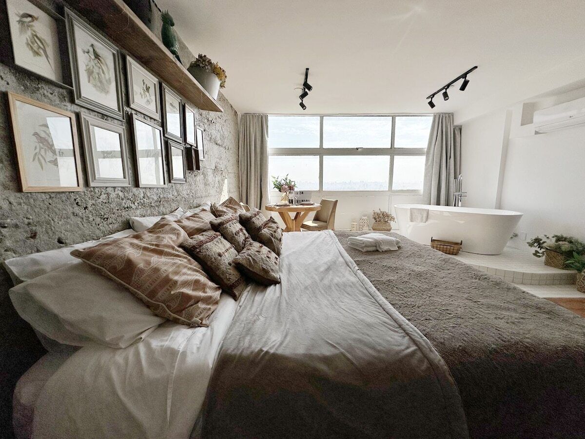 Um quarto com uma cama grande, uma banheira e uma janela com cortinas.