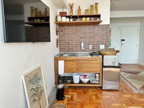 Eine kleine Küche mit Ziegelrückwand, Holzschränken und einem Kühlschrank.
