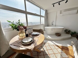 Ein modernes Badezimmer mit einer freistehenden Badewanne, einem großen Fenster und Blick auf die Stadt.