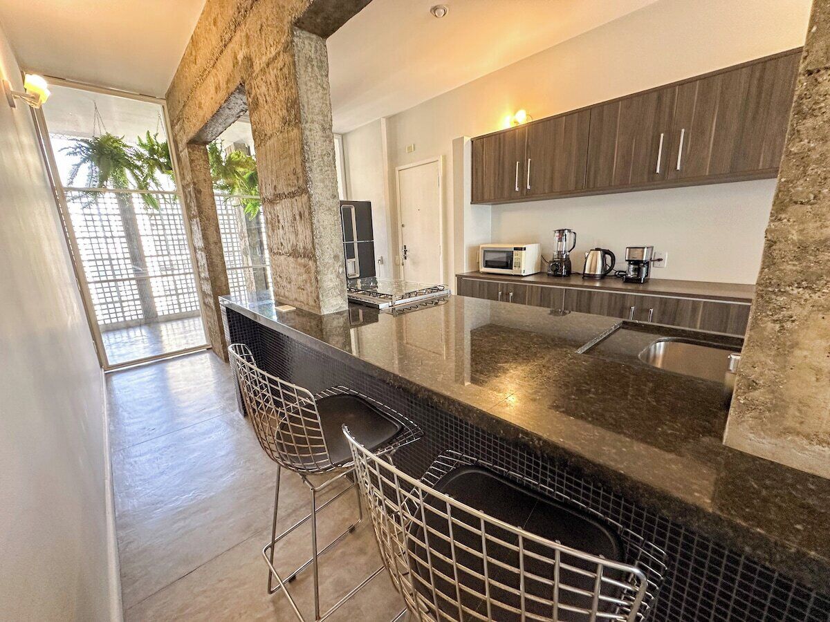 A modern kitchen with a bar area, a stove, a microwave, and a coffee maker.