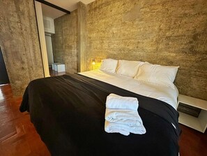 Une chambre moderne avec un grand lit, une lampe de chevet et un plancher en bois.