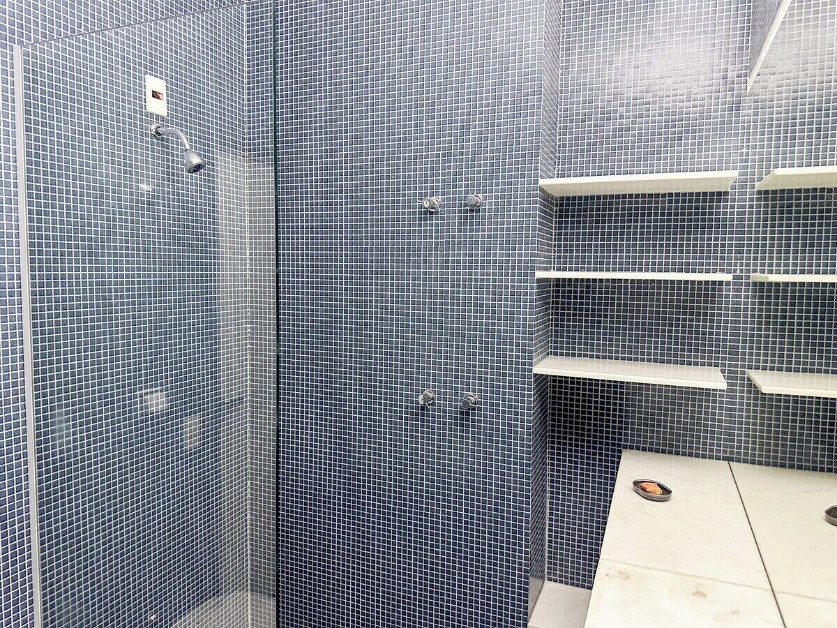 A bathroom with a tiled wall, a shower area, and a toilet.