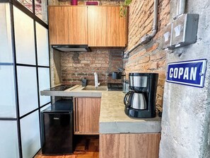 A compact kitchen with wooden cabinets, a coffee maker, and a small refrigerator. - 3205B (São Paulo)