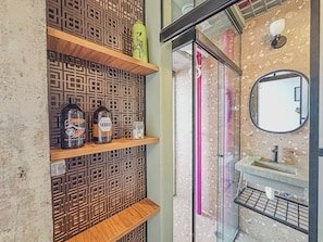 A bathroom with a patterned wall, a shelf with bottles, a mirror, and a sink. - 3205B (São Paulo)