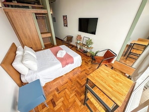 A bedroom with a bed, a desk, a chair, and a TV on the wall. - 3205B (São Paulo)