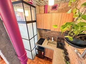 A compact kitchen with a built-in stove, a small sink, and wooden cabinets. - 3205B (São Paulo)