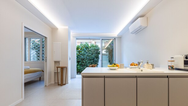 Een moderne keuken met een centraal eiland, een inbouwoven en een raam met uitzicht op een tuin.