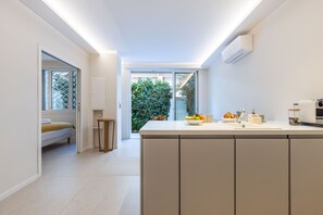 Una cocina moderna con una isla central, horno empotrado y ventana con vistas a un jardín.