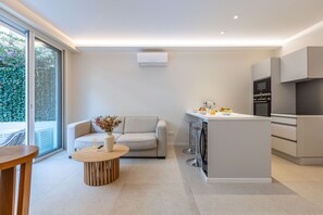 A modern kitchen with a central island, a built-in oven, and a large window providing a view of greenery outside. - 2-Bedroom Apartment with Terrace - Pointe Croisette A2B267 (Cannes)