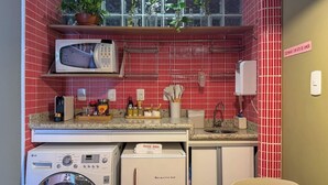 Uma cozinha compacta com micro-ondas, máquina de lavar e um pequeno frigorífico.