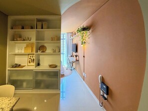 A modern interior with a white shelving unit, a desk with a chair, and a telephone on the wall. - 0704B (São Paulo)
