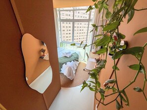 Ein Schlafzimmer mit einem Bett, einem Nachttisch, einem Spiegel und einer Topfpflanze.