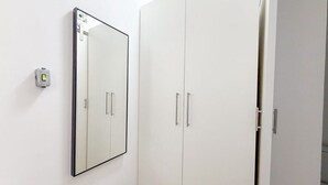 Ein weißer Kleiderschrank mit zwei Türen und einem Spiegel an der Wand.