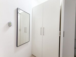 A white wardrobe with two doors and a mirror on the wall. - 0202B (São Paulo)