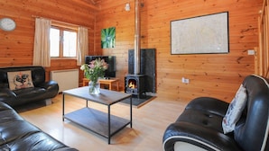 Ein gemütliches Blockhaus-Interieur mit Kamin, Ledersofas, einem Couchtisch und einer Karte an der Wand.