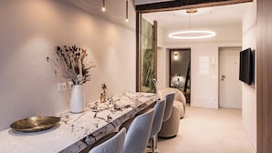 Un espace repas moderne avec une table en marbre, des chaises blanches et un vase contenant des fleurs séchées.