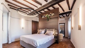Une chambre à coucher avec un grand lit, des poutres en bois au plafond et un luminaire moderne.