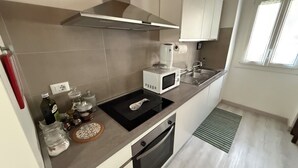 Une cuisine moderne équipée d’un four à micro-ondes, d’un évier et d’une cuisinière. On peut voir des bocaux et une bouteille sur le plan de travail.