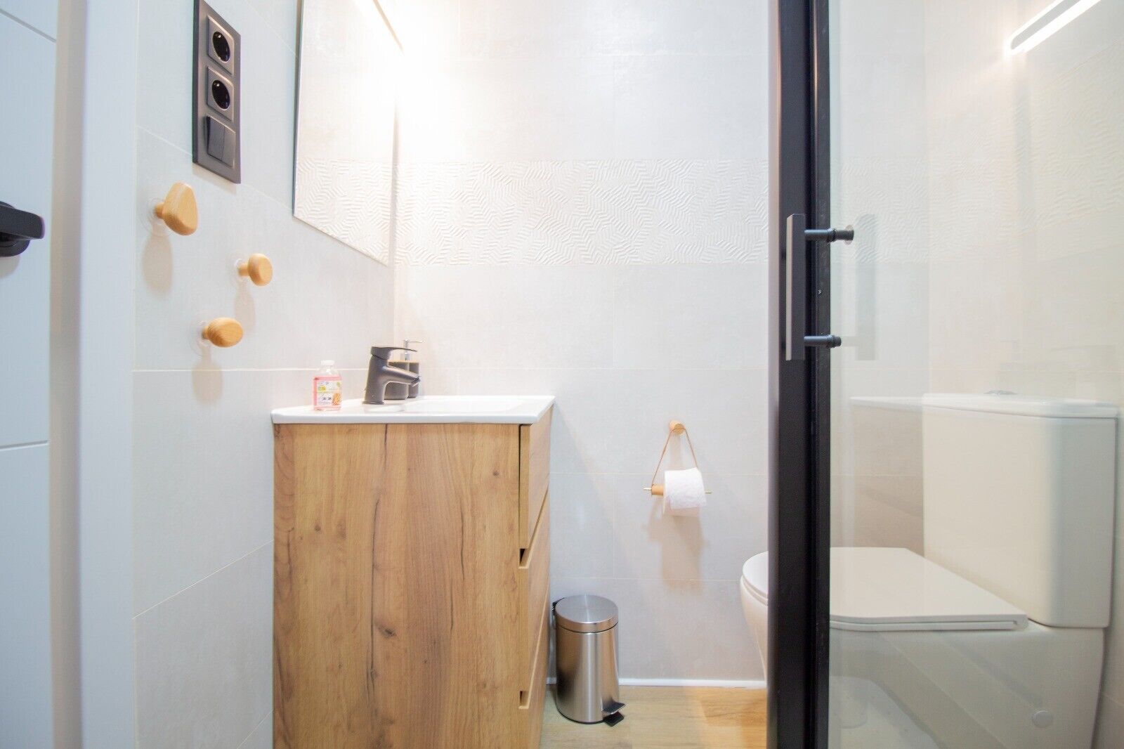 Un baño moderno con tocador de madera, inodoro y cabina de ducha de vidrio.