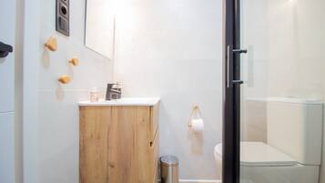 Un baño moderno con tocador de madera, inodoro y cabina de ducha de vidrio.