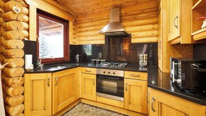 A log cabin kitchen with wooden cabinets, a gas stove, an oven, and a microwave.