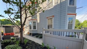 A residential building with a fenced backyard, a tree, and a small garden with various plants and flowers. - Spacious & sunny 4-bedroom home in the heart of Portland's charming West End (Portland)