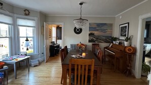 A spacious dining area with a wooden table and chairs, a chandelier, and a piano. - Spacious & sunny 4-bedroom home in the heart of Portland's charming West End (Portland)