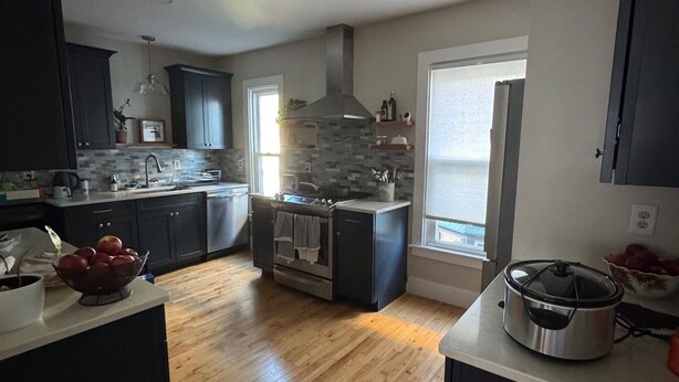 A modern kitchen with dark cabinets, a central island, and a large stove. - Spacious & sunny 4-bedroom home in the heart of Portland's charming West End (Portland)