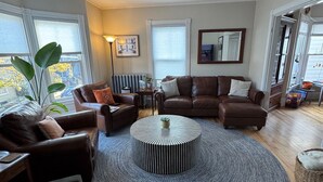 A spacious living room with a large round rug, leather sofas, and a coffee table. - Spacious & sunny 4-bedroom home in the heart of Portland's charming West End (Portland)