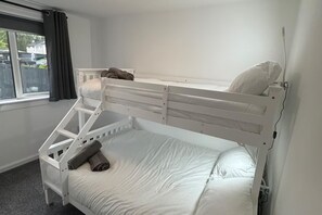 Un lit superposé avec un lit en bas, une petite échelle et un seul oreiller sur le lit du haut.