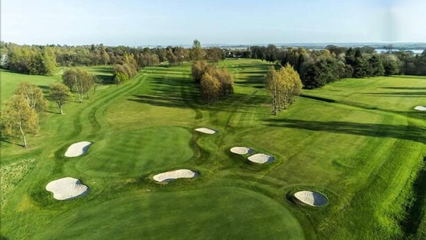 Golfkenttä, jossa on hiekkabunkkereita ja puita.