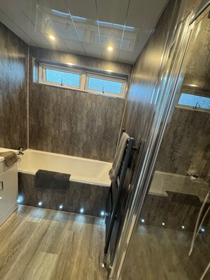 Ein modernes Badezimmer mit Badewanne, Dusche und Fenster.