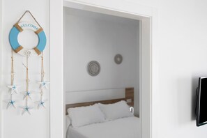 Ein Zimmer mit Bett, einem an der Wand befestigten Fernseher und einem Willkommensschild mit Sternen.